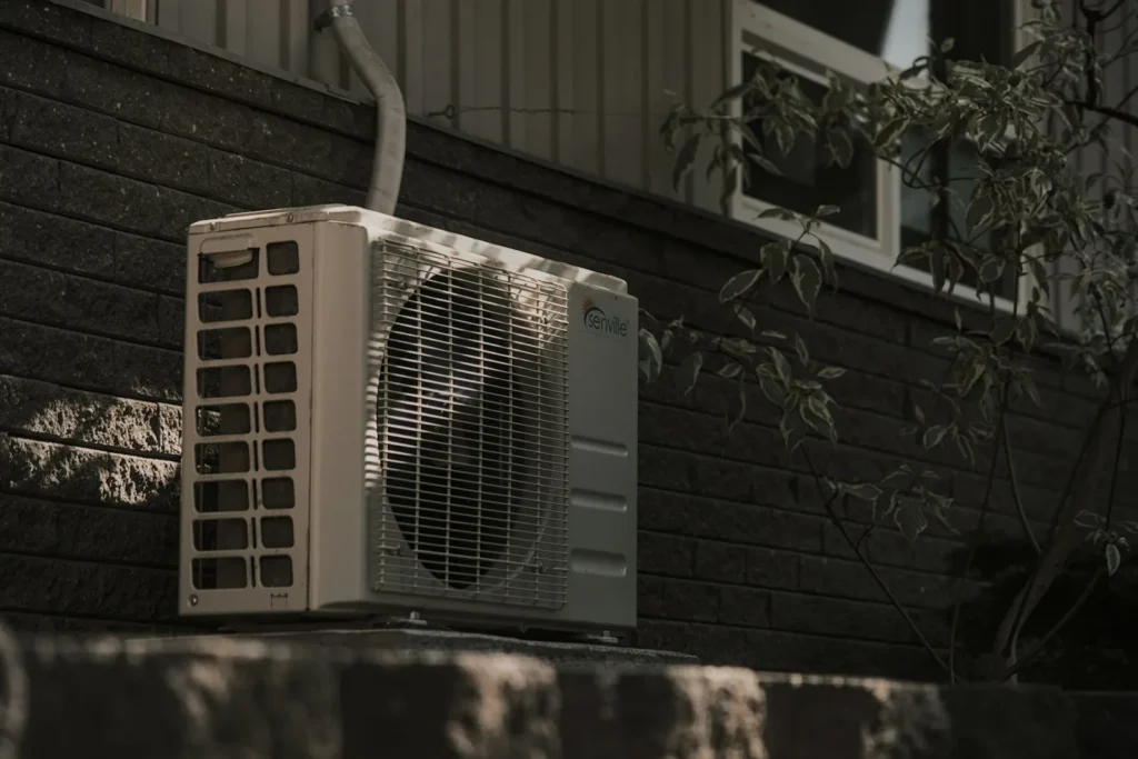 Outdoor air conditioning condenser unit mounted on a brick wall