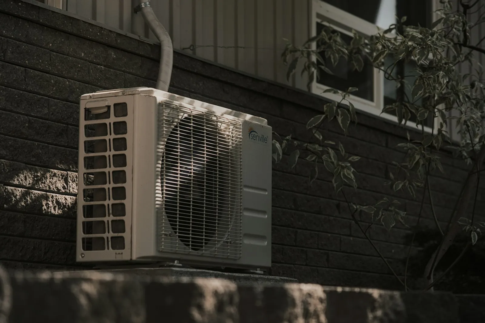Outdoor air conditioning condenser unit mounted on a brick wall