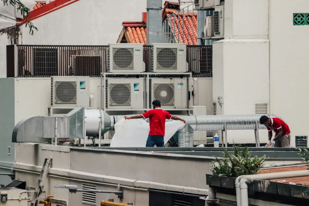 Two HVAC technicians working on a rooftop unit
